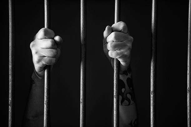 Hands holding a bar of prison