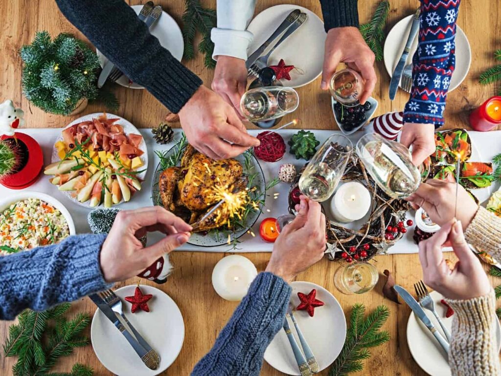 Baked turkey christmas dinner christmas table is served with turkey decorated with bright tinsel candles fried chicken table family dinner top view hands frame 1