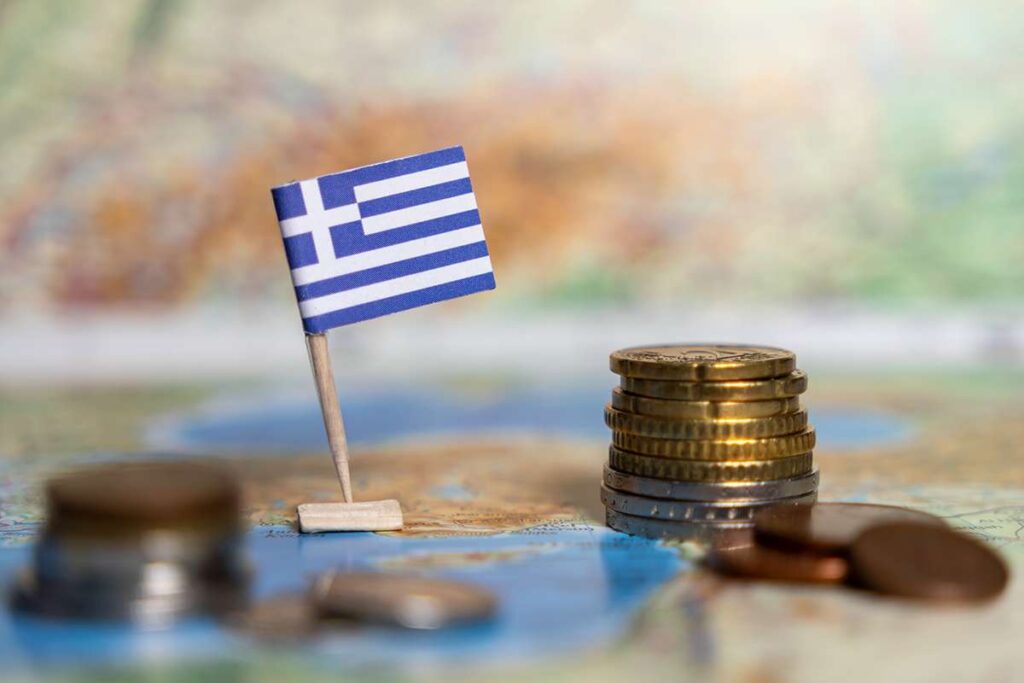 Greek,Flag,With,Coins,On,A,Map,Representing,The,Economy,